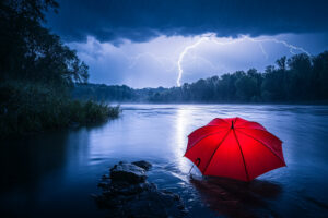 Roter Schirm am See liegend während Gewitter